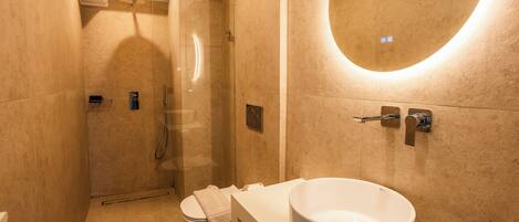 Un baño moderno con lavamanos grande, inodoro y cabina de ducha con mampara de vidrio.