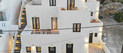 A modern building with multiple balconies, outdoor seating areas, and a staircase.