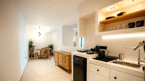 Una cocina moderna con armarios blancos, un lavavajillas negro y una mesa de comedor de madera con sillas.
