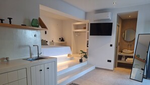 Una cocina moderna con un lavamanos integrado, un comedor con mesa y sillas, y una sala de estar con sofá y mesa de centro.