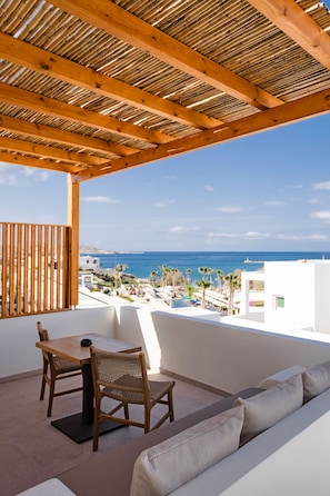 Un balcone con soffitto in legno, un tavolo con sedie e un divano.