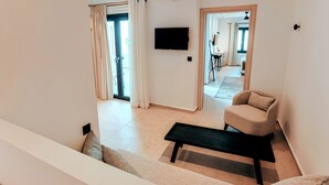 Una sala de estar moderna con un sofá, una mesa de centro y un televisor montado en la pared.