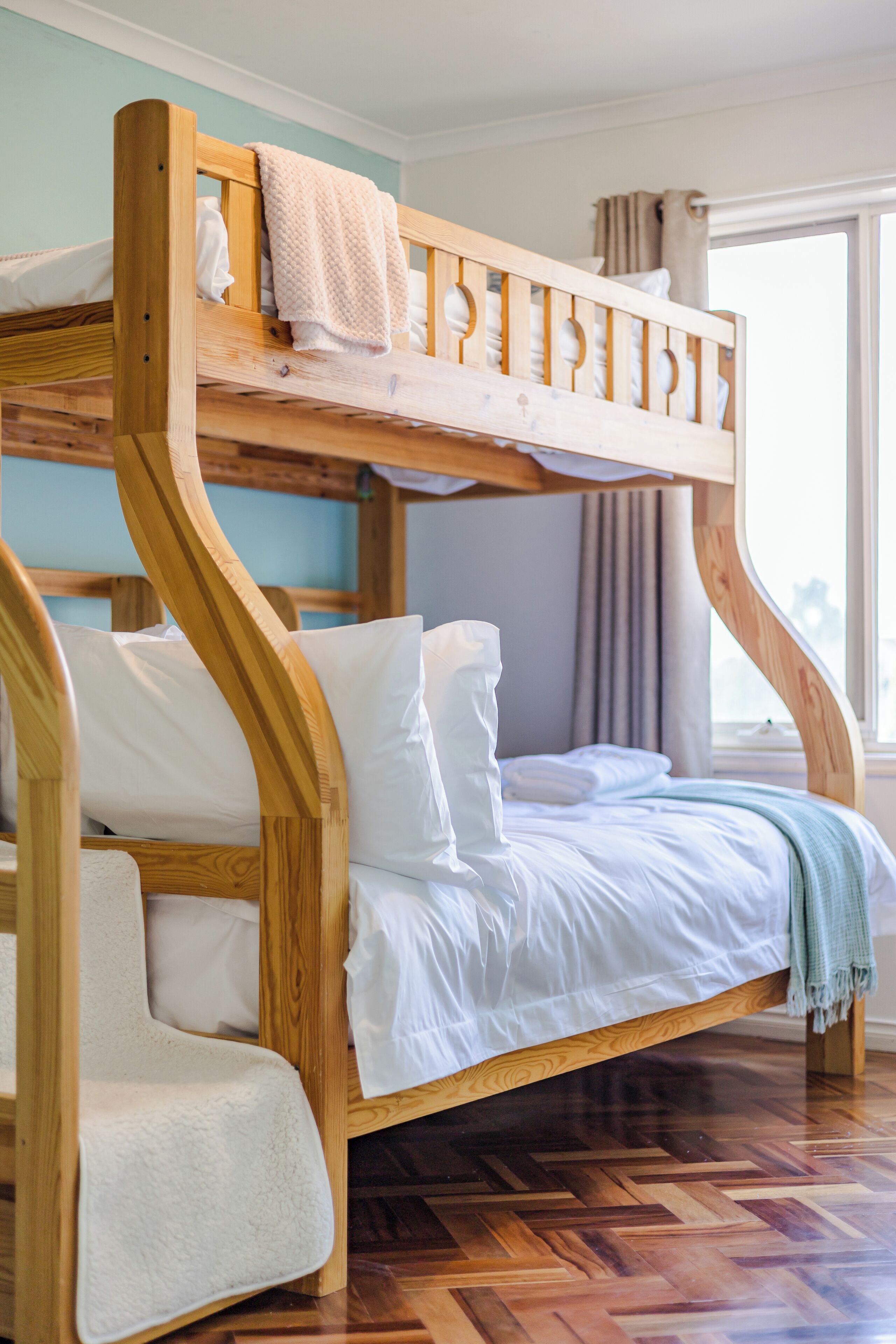 A bunk bed with a wooden frame and white bedding.