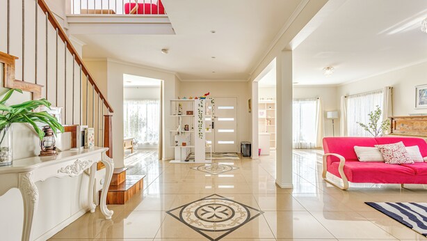 A spacious living area with a staircase, a bright red sofa, and a white console table. - StayAU Family Home in Caroline Springs (Caroline Springs)