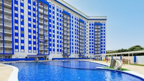 A large swimming pool with a slide, surrounded by a modern building with blue and white vertical stripes. - Mar de Oropesa II by Interhome (Oropesa del Mar)
