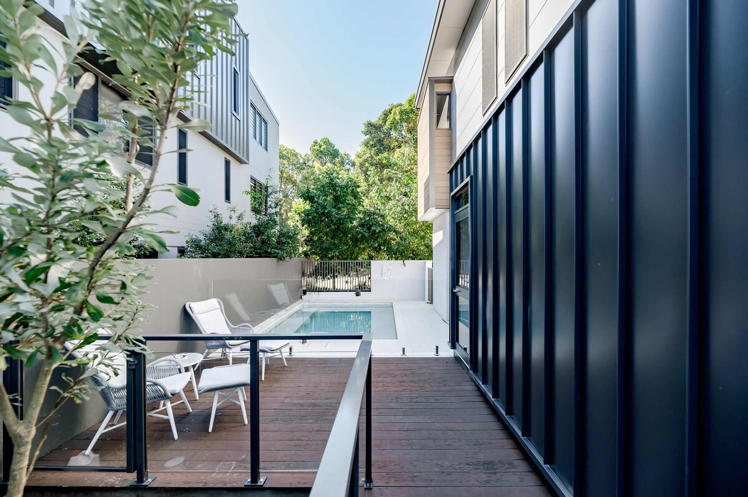 A modern outdoor pool area with lounge chairs and a wooden deck.