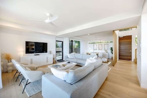 Una sala de estar moderna con un televisor de pantalla plana grande, un conjunto de sofá, una mesa de centro y un comedor con una mesa y sillas.