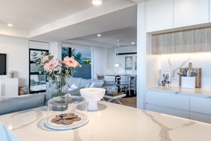A modern kitchen with a marble countertop, a vase with flowers, and a bowl with a candle.