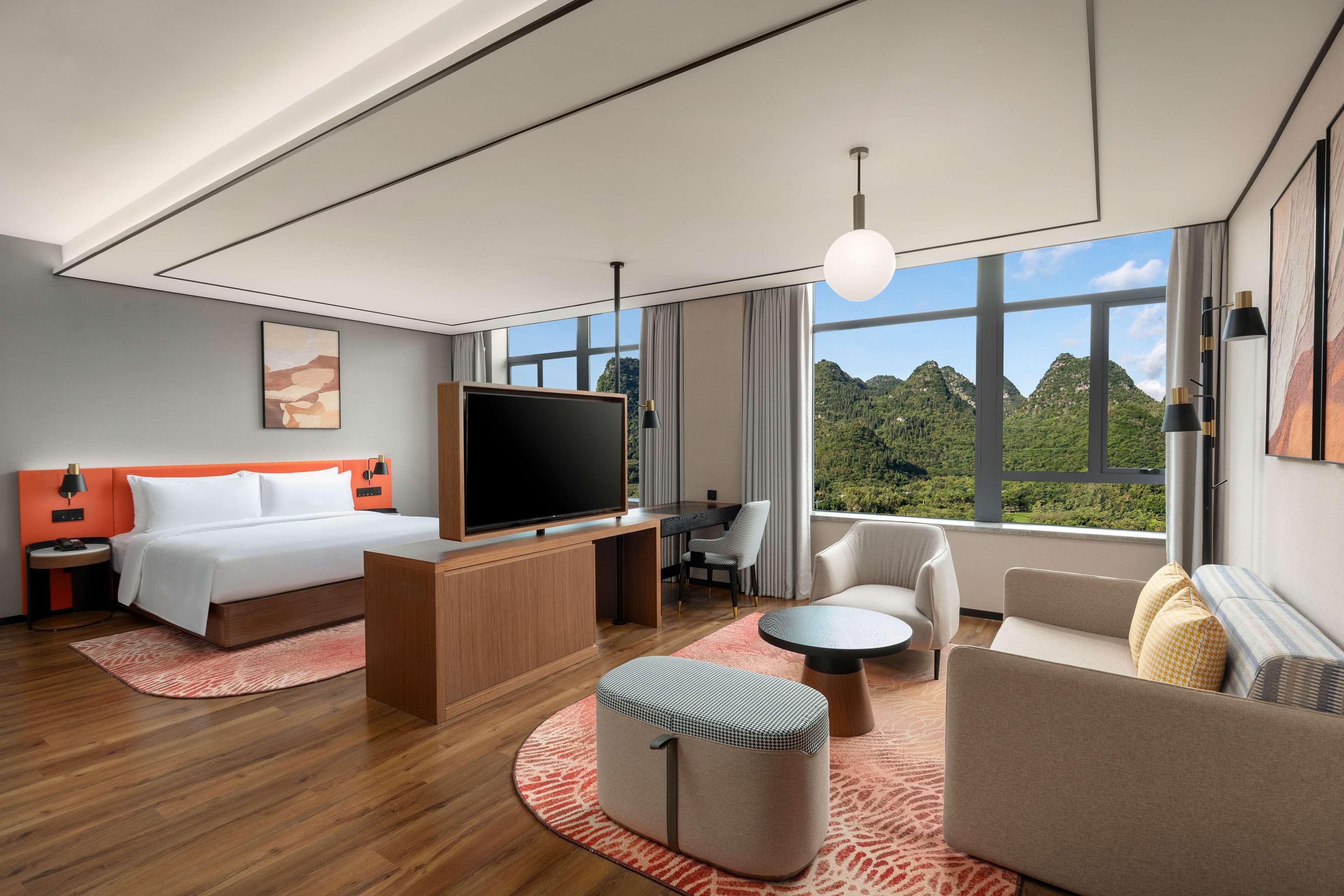 Une chambre d’hôtel moderne dotée d’un grand lit, d’un bureau, d’une télévision, d’un canapé et offrant une vue sur les montagnes.