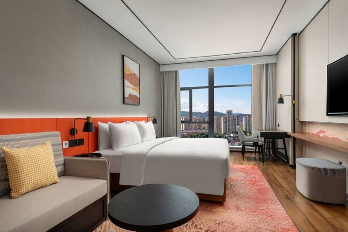 Una habitación de hotel con cama, sofá, escritorio y televisión.