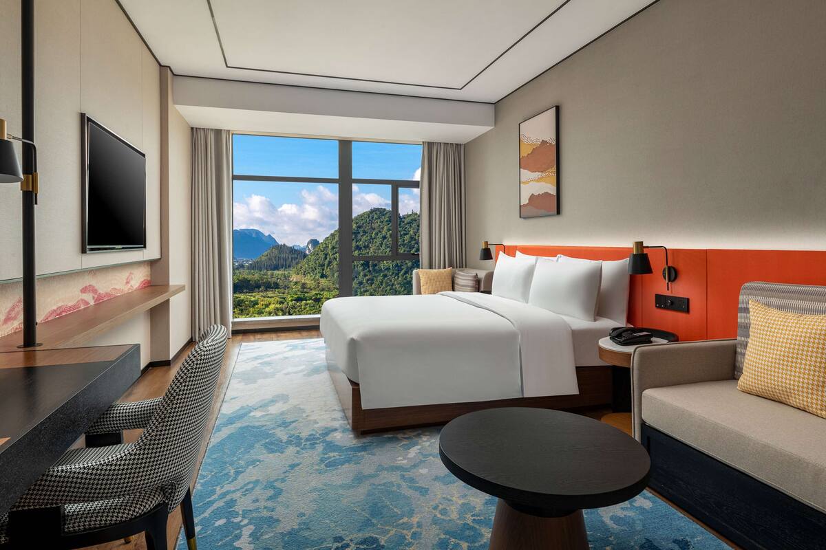 Una camera d'albergo con un letto grande, un divano, una scrivania e una televisione.