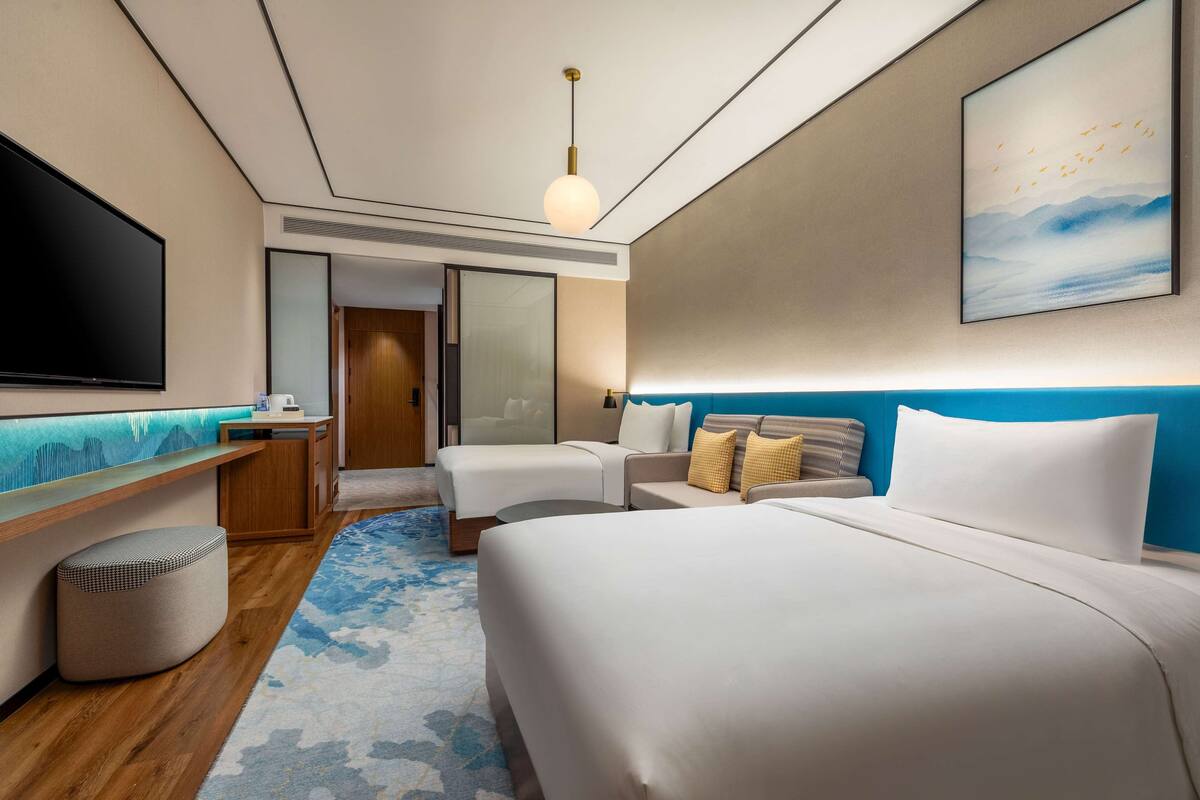 Camera d'albergo con un letto grande, una scrivania con televisore a schermo piatto, un divano e un'opera d'arte appesa al muro.