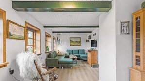 A cozy living room with a green sofa, a wooden rocking chair, and a television. - 1 bedroom awesome home in Rudkøbing (Rudkøbing)