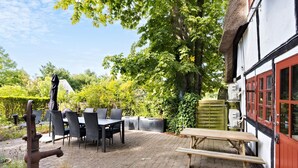 An outdoor patio with a table and chairs, a wooden bench, and a water spigot. - 1 bedroom awesome home in Rudkøbing (Rudkøbing)