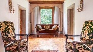 Ein Zimmer mit Holzboden, einer Bank mit Kissen, gemusterten Stühlen und einem Teppich mit Muster.