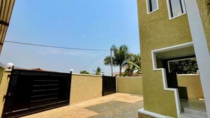 A gated courtyard with a paved floor, a staircase leading to a door, and a wall with a window.