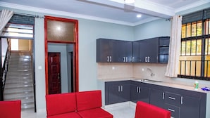 A modern kitchen with dark cabinets, a red sofa, and a staircase leading to an upper floor.