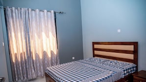 A bedroom with a bed, wooden headboard, and a curtain.