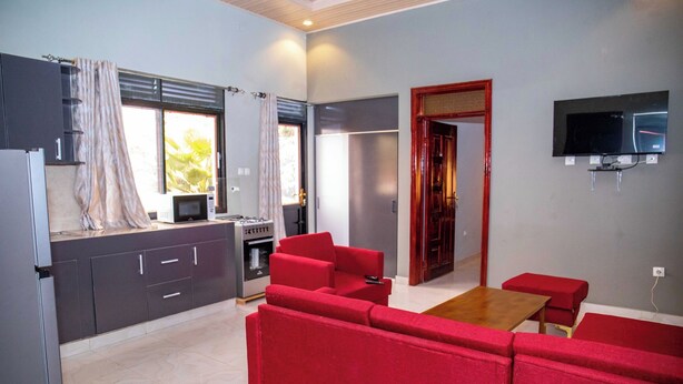 A modern kitchen with a microwave, stove, and refrigerator. There is a red sofa and a wooden table in the living area.