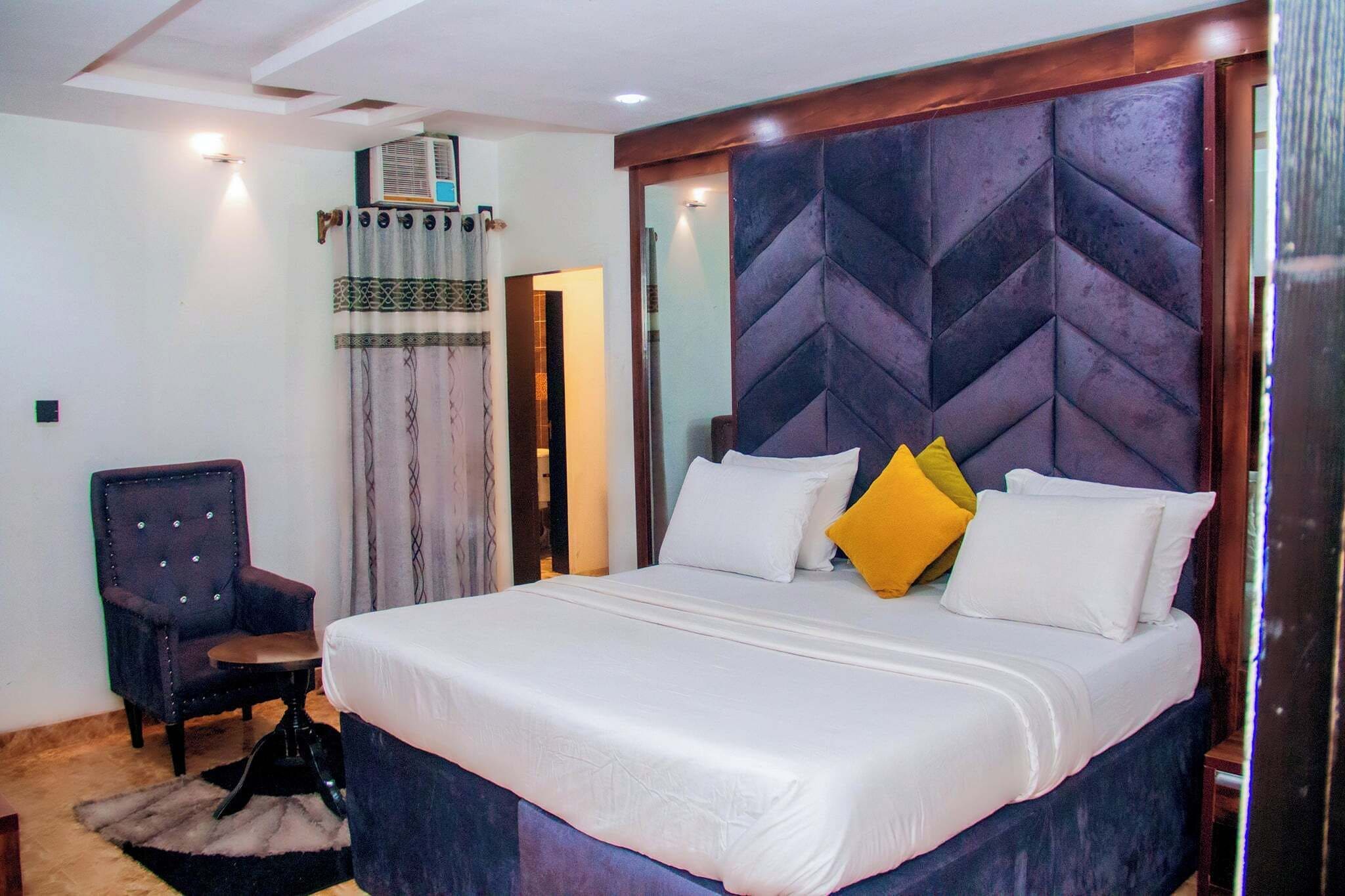 A neatly arranged bedroom with a large bed, a chair, and a small table.