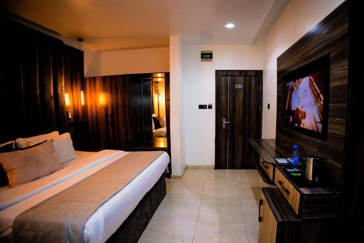 Una habitación de hotel con una cama grande, un televisor en la pared y un armario de madera.