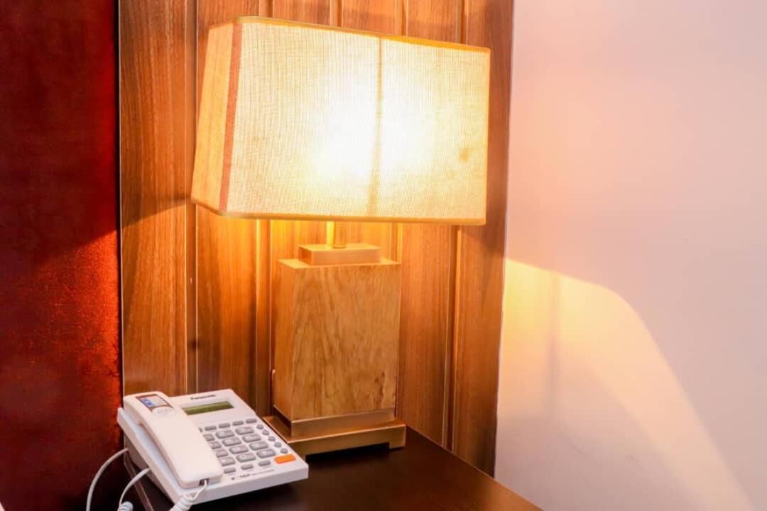 A wooden wall with a white telephone and a lamp.