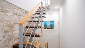 A staircase with wooden steps and metal railings, a stone wall, and a painting on the wall. - GuestHost - Il Torrino al Porto Room (Bisceglie)