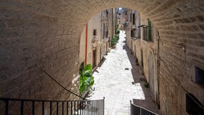 A narrow stone-paved alleyway with a stone archway, flanked by buildings with balconies and windows. - GuestHost - Il Torrino al Porto Room (Bisceglie)
