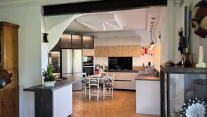 Una cocina moderna con una isla central, armarios de madera y un comedor con sillas.