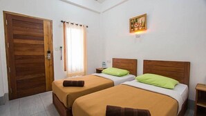 Une chambre d’hôtel avec deux lits, des têtes de lit en bois, un tableau au mur et une porte avec un rideau.