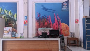 Un comptoir d’accueil orné d’une grande affiche représentant un plongeur sous l’eau, d’une horloge et de divers panneaux, dont un logo PADI.