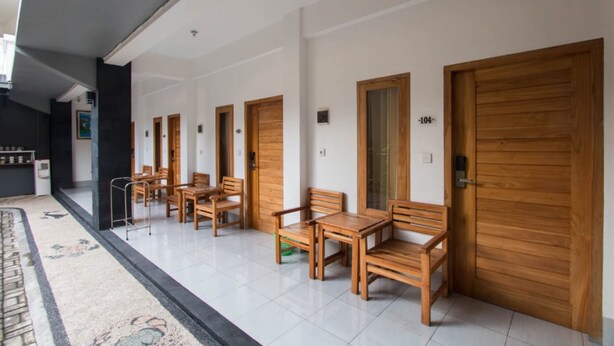 Un couloir avec des portes en bois, un sol carrelé et un coin salon avec des meubles en bois.