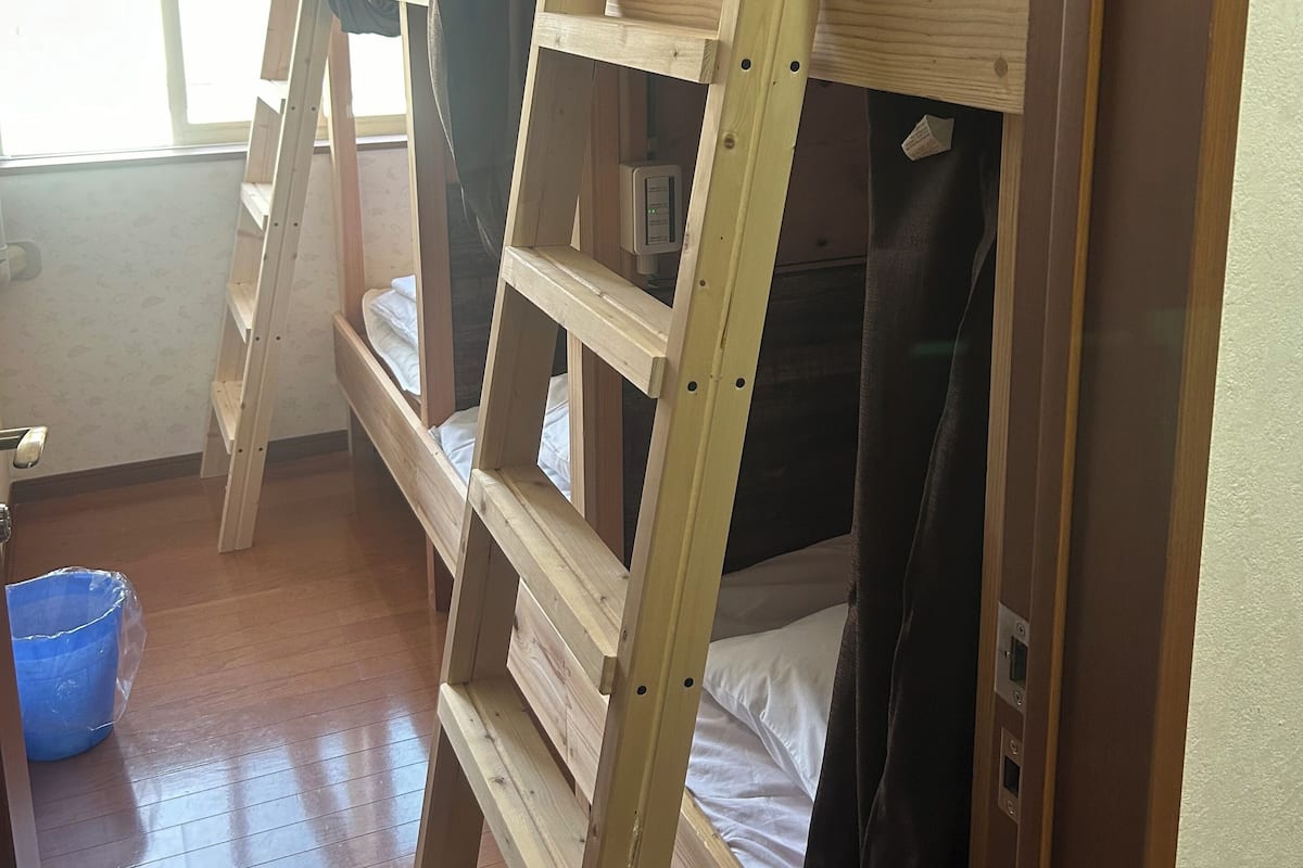 A bunk bed room with a wooden ladder and a window.