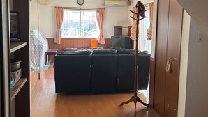 A living room with a sofa set, a television, and a ceiling fan. - Guesthouse Aizu - Hostel (Tanabe)