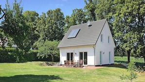 A single-story house with a sloped roof, a patio with outdoor furniture, and a small garden area. - Ferienhaus Kiebitz, Plau am See (Plau am See)