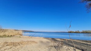 A sandy beach with a clear blue sky and calm water. - Ferienhaus Kiebitz, Plau am See (Plau am See)