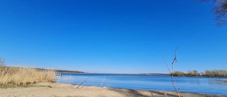 A sandy beach with a clear blue sky and calm water.