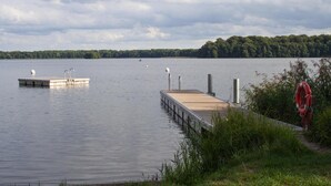 A calm lake with two docks extending into the water, surrounded by greenery and a cloudy sky. - Wunderschoner Bungalow Louise in Dobbertin (Dobbertin)