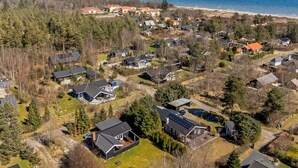 An aerial view of a residential area with houses, a beach, and a forested area.