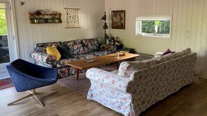 A cozy living room with a floral sofa, a blue chair, and a wooden coffee table.