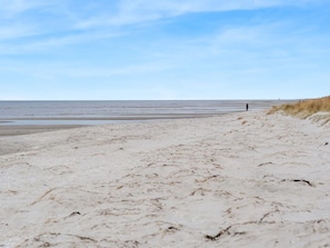 Ein Strand mit einer Person, sandigem Boden und blauem Himmel.