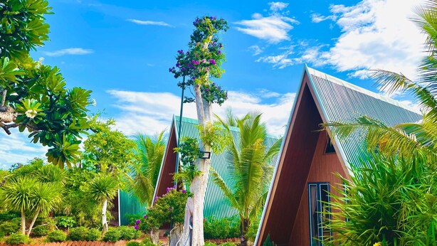 A resort with triangular roofs, lush greenery, and a clear blue sky. - Xanh Homestay (Phu Cat)