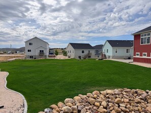 A residential area with multiple houses, a well-maintained lawn, and a stone wall.