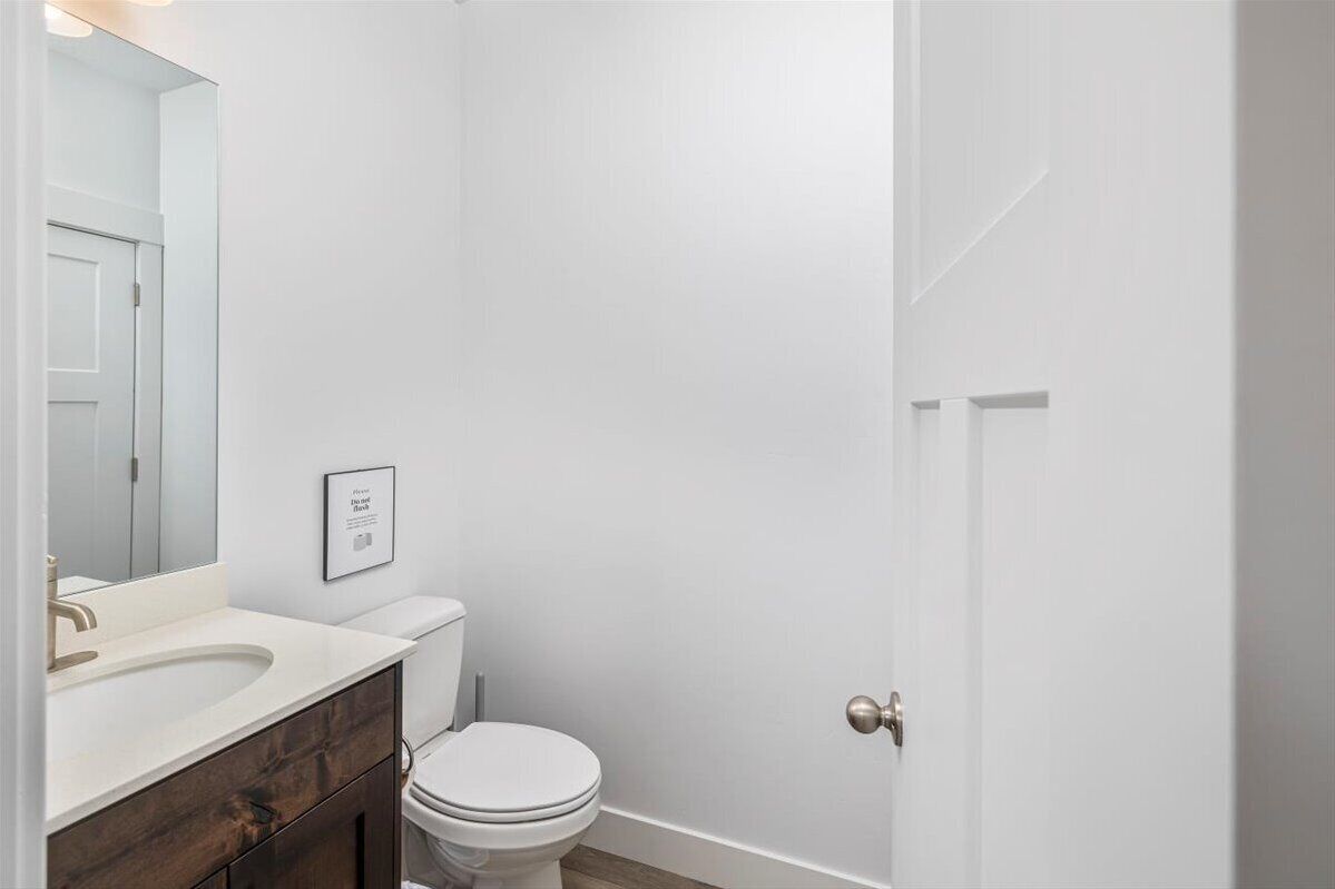 Une salle de bain avec un lavabo, des toilettes et un miroir, le tout de couleur blanche.