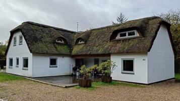 A two-story house with a thatched roof and white exterior walls.