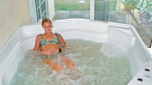 Iemand zit in een jacuzzi, met een raam op de achtergrond.