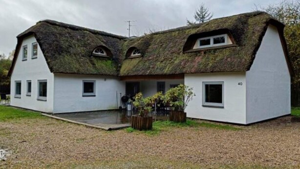 Een rieten dak en witte buitenmuren sieren dit woonhuis met twee verdiepingen.