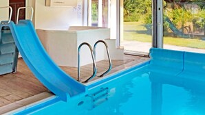 Een zwembad met een blauwe glijbaan, metalen leuningen en een houten terras.