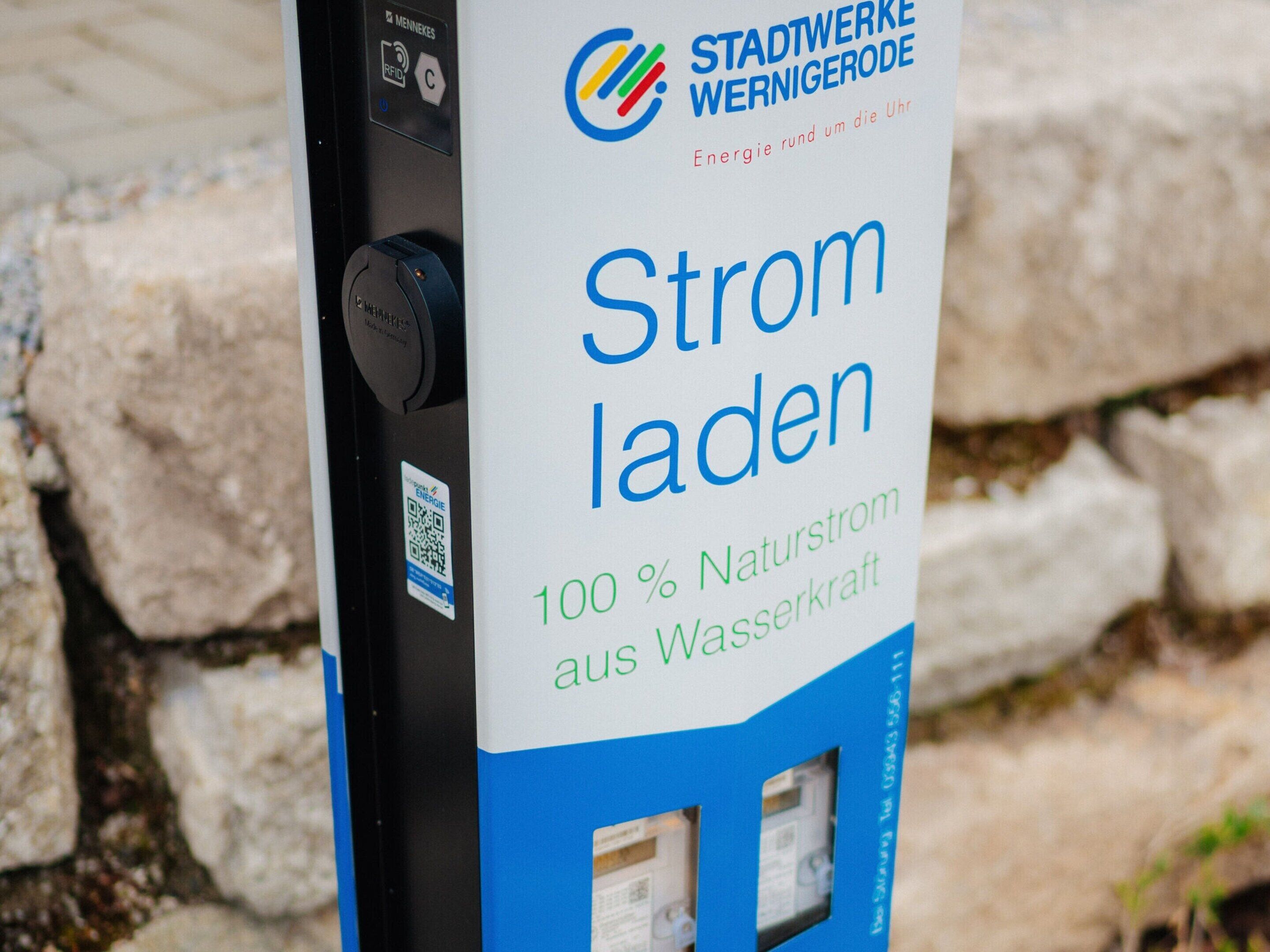 A public charging station with a sign indicating it is powered by 100% natural water power.