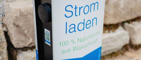 A public charging station with a sign indicating it is powered by 100% natural water power.